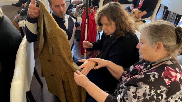 Vrouw met visuele beperking houdt haar blindenstok vast en voelt aan kostum van een theatervoorstelling.